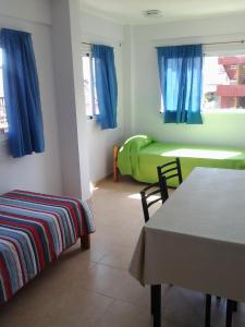 a room with a bed and a table and blue curtains at Punta Gesell in Villa Gesell