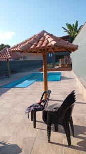 a patio with two chairs and a wooden umbrella at Chácara do tio Tuta in Araçariguama