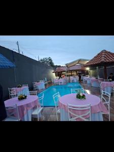 a swimming pool with tables and chairs next to a pool at Chácara do tio Tuta in Araçariguama