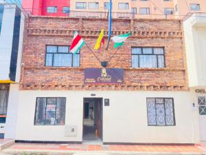 a building with three flags on the front of it at Hotel Colonial El Gran Fénix in Tunja