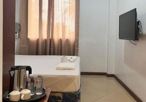 a room with a bed with a table and a tv at Kyleville Resort by Hiverooms in Dalaguete