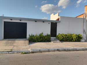 a white building with a black door on a street at Casa em Piranhas com piscina in Piranhas