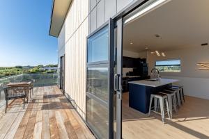 a kitchen and dining area with sliding glass doors and a balcony at Sleek, Elevated Views, Hidden - KK43103 in Kaikoura +21 photos