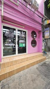 a pink building with steps in front of a store at Hostel In The City in Pom Prap