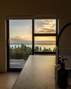 a kitchen with a view of the ocean through a sliding glass door at Sleek, Elevated Views, Hidden - KK43103 in Kaikoura