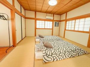 two beds in a large room with windows at 徳治郎の宿 in Izumi-Sano