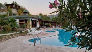a pool with chairs and a house in the background at Angels Garden Hotel in Olympos