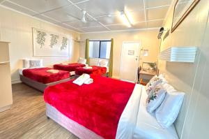 a hotel room with two beds with red sheets at Charters Towers Motel in Charters Towers +21 photos