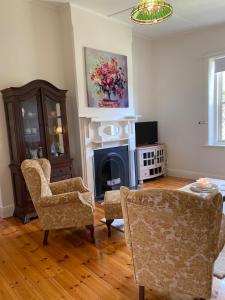 a living room with two chairs and a fireplace at Riverstone Cottage at Murray Bridge in Murray Bridge