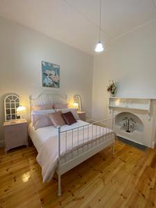 a bedroom with a white bed and a fireplace at Riverstone Cottage at Murray Bridge in Murray Bridge
