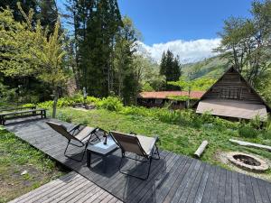 a wooden deck with two chairs and a table at Lodge GRAMP アルプスの見える隠れ家 in Omachi