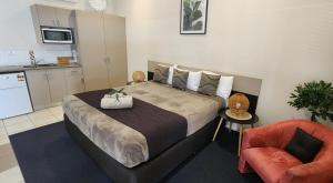 a bedroom with a bed and a chair and a kitchen at Charters Towers Motel in Charters Towers