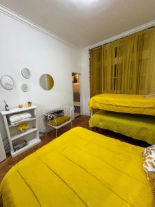 two beds in a room with yellow sheets at corazón obelisco 2 in Buenos Aires