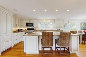 a kitchen with white cabinets and a island with bar stools at Harborside Retreat in Falmouth