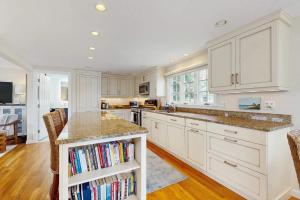 a kitchen with white cabinets and a island with books at Harborside Retreat in Falmouth