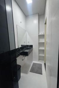 a white bathroom with a sink and a mirror at Hospedagem Caripi in Barcarena
