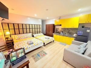 a living room with a bed and a kitchen with yellow cabinets at Lyric and Melody Collection in Santa Catalina +23 photos