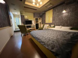 a bedroom with a large bed and chairs in it at ホテルQ adult only in Kashiwazaki