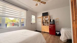 a bedroom with a white bed and a red refrigerator at Les Petits Studios du bord de l'eau in Saint-Joseph-de-la-Rive