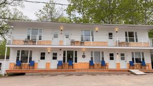a white house with blue chairs in front of it at Les Petits Studios du bord de l'eau in Saint-Joseph-de-la-Rive