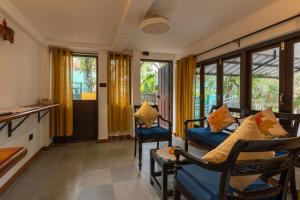 a living room with a couch and chairs and windows at Encontro Homestays in Dona Paula