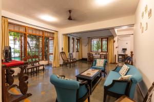 a living room with blue chairs and tables at Encontro Homestays in Dona Paula