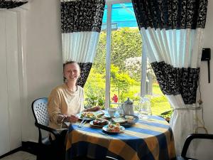 a woman sitting at a table with a plate of food at Hidden Treasure in Nuwara Eliya +26 photos