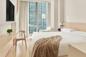 a white bedroom with a bed and a desk and a chair at The Times Square EDITION New York in New York +49 photos