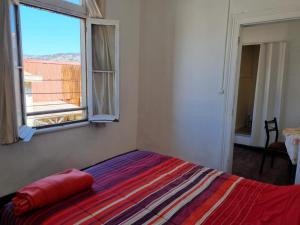 a bedroom with a bed with a colorful blanket and a window at Hostal Playa Ancha in Valparaíso