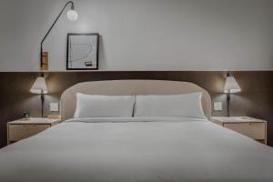 ein Schlafzimmer mit einem großen weißen Bett und zwei Lampen in der Unterkunft Hotel Longmont in Longmont