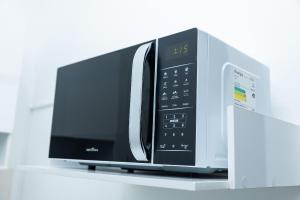 a microwave oven sitting on top of a shelf at Loft Completo com Smart TV e Frigobar Compacto 08 in Presidente Prudente