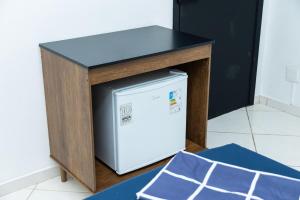 a microwave under a table with a refrigerator underneath it at Loft Completo com Smart TV e Frigobar Compacto 08 in Presidente Prudente