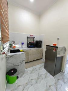 a kitchen with a counter and a sink and a refrigerator at Asyhani Cottage in Bachok