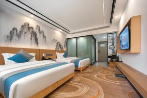 a hotel room with two beds and a flat screen tv at Shenzhoujie International Hotel-3min to Forest Park East Gate&Tickets reserve-Personal Itinerary service- Shuttle service in Zhangjiajie