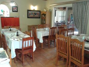 a dining room with white tables and wooden chairs at Kalahari Guest House in eMalahleni