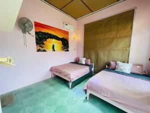 a bedroom with two beds and a fan at Homestay Đại Nghĩa in Quảng Ngãi