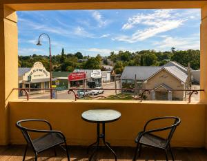 a table and two chairs on a balcony with a view of a town at Golden Age Hotel in Omeo