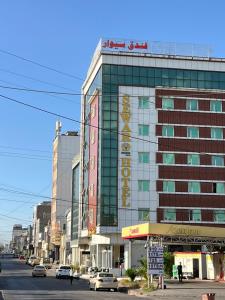 a large building on a city street with cars parked at فندق سيوار in Erbil