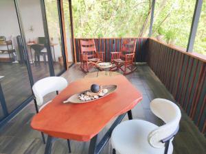 a table and chairs on a screened porch with a table and a plate at Cocolhu Treehouse & Ocean View in Tamarindo