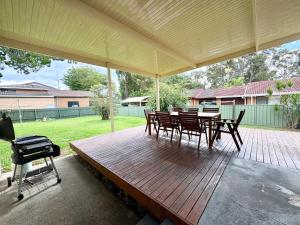 a wooden deck with a grill and a table and chairs at Horace Street 8 in Shoal Bay