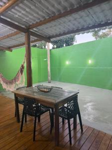 a wooden table and chairs on a porch with a green wall at Chalé Lunar in Arraial d'Ajuda