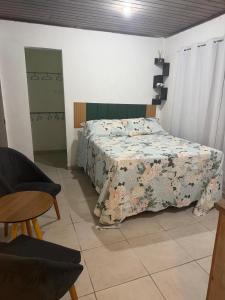 a bedroom with a bed with a floral bedspread at Chalé Lunar in Arraial d'Ajuda