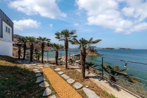 a pathway with palm trees next to the water at M129 Pension Namhae in Namhae +5 photos