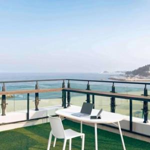a white table and chairs on a balcony with the ocean at Yangyang Hotel Unbound House in Yangyang