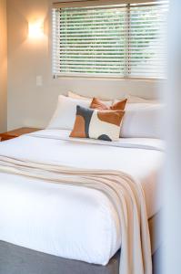 two white beds in a bedroom with a window at Maleny Terrace Cottages in Maleny