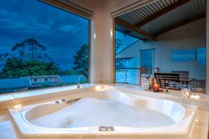 a bath tub in a bathroom with a large window at Maleny Terrace Cottages in Maleny