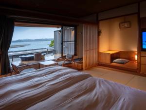 a bedroom with a large bed with a view of the ocean at Hamabenoyado Kameya in Toba