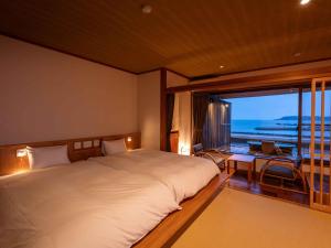 a bedroom with a large bed and a large window at Hamabenoyado Kameya in Toba