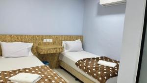 two beds in a small room withermottermottermott at Winnieys Boutique Hotel in Kuala Lumpur