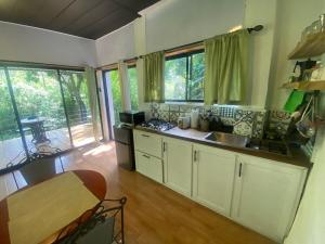 a kitchen with white cabinets and a table and windows at River View-Camping Add-On Available in Jarabacoa